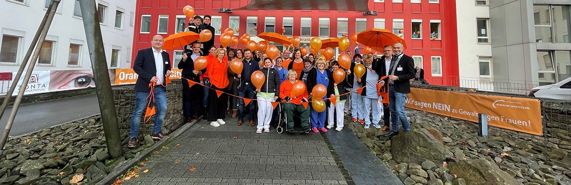 Mitarbeiter des Klinikums Westfalen haben sich mit orangefarbenen Schirmen und Luftballons vor dem Knappschaftskrankenhaus Dortmund postiert