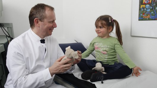 Chefarzt Dr. Stefan Orth im Gespäch mit einem kleinen Mädchen
